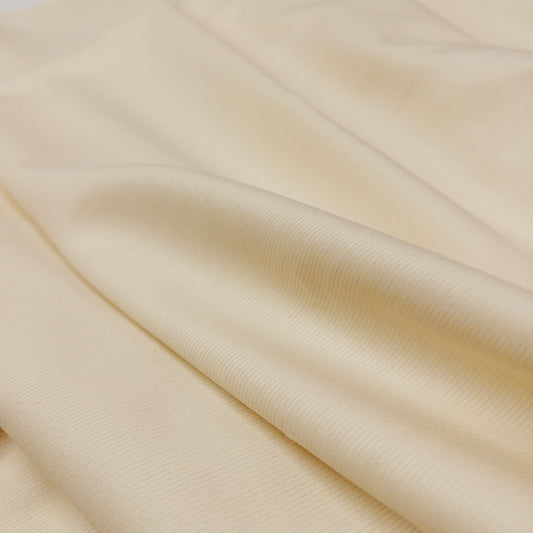 view of the face of fabric with slight folds in this 100% organic cotton baby corduroy apparel fabric is soft white