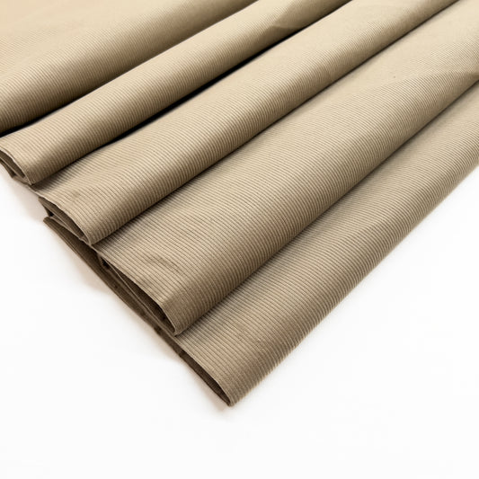 Cotton corduroy garment fabric in light brown shown folded.