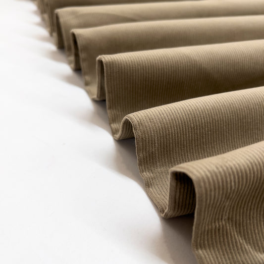 Corduroy fabric shown folded in a ribbon to demonstrate the structure of this mid weight fashion fabric.